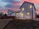 A spacious backyard featuring a lush green lawn, patio set, and privacy fence during a beautiful sunset at 718 Fairhaven St, Castle Rock, CO 80104