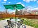 Backyard patio set with a table, umbrella, and four chairs against a backdrop of a wooden fence at 718 Fairhaven St, Castle Rock, CO 80104