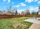 Fenced backyard featuring a grassy area and a concrete patio set under a sunny, partly cloudy sky at 718 Fairhaven St, Castle Rock, CO 80104