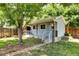 Charming light blue home with a small porch, stone walkway, and fenced yard shaded by a mature tree at 1215 S Ivanhoe Way, Denver, CO 80224
