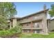 Three-story condo building featuring red entry doors and wood railings overlooking manicured landscaping at 695 Manhattan Dr # 109, Boulder, CO 80303