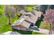 An elevated view of a well-maintained brick home featuring a tile roof, lush yard, and a car parked in the driveway at 16 Wedge Way, Littleton, CO 80123