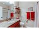 Bathroom with granite countertops, cherry wood cabinets, and a tiled shower and red accent towels at 4322 N Meadows Dr, Castle Rock, CO 80109