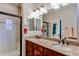Bathroom with double sink vanity, granite countertops, and a tiled shower with black trim at 4322 N Meadows Dr, Castle Rock, CO 80109