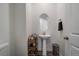 A pedestal sink, decorative shelving, and neutral color palette create a serene ambiance in this well-lit powder room at 8390 S Cody Way, Littleton, CO 80128