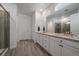 Modern main bathroom showcasing double sinks, granite countertops, wood-look tile flooring, and a glass-enclosed shower at 8390 S Cody Way, Littleton, CO 80128