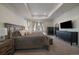 Bright main bedroom featuring a tray ceiling, large windows, plush furnishings, and elegant decor at 8390 S Cody Way, Littleton, CO 80128