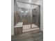 Modern shower stall with sleek glass doors, contemporary gray tiling, and a built-in bench for a spa-like experience at 8390 S Cody Way, Littleton, CO 80128
