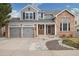 Charming two-story home featuring a brick facade, gray siding, attached garages, and manicured front yard at 787 Huntington Pl, Highlands Ranch, CO 80126