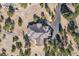 Aerial view of a house with a dark roof surrounded by lush trees and a long driveway at 32569 El Diente Ct, Evergreen, CO 80439