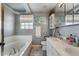 Bright bathroom featuring a soaking tub, updated vanity with double sinks, and a large mirror at 19917 Mitchell Cir, Denver, CO 80249