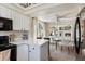Modern kitchen with white cabinets and countertops, black appliances, and open flow to the dining area at 19917 Mitchell Cir, Denver, CO 80249