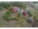 Wide aerial view of a two-story home and guest house surrounded by rolling hills and mature trees at 2100 Bibles Hill Dr, Franktown, CO 80116