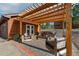 Inviting covered patio featuring stylish wood furniture, a brick-paved floor, and outdoor access to a manicured lawn at 2100 Bibles Hill Dr, Franktown, CO 80116