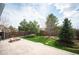 Spacious backyard featuring a brick patio, fire pit, lush lawn, and privacy fence at 5875 Raleigh Cir, Castle Rock, CO 80104