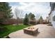 Brick fire pit on a large brick patio surrounded by green lawn and a privacy fence at 5875 Raleigh Cir, Castle Rock, CO 80104