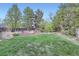 Well-maintained backyard featuring a vibrant green lawn, mature trees, and charming garden beds at 7380 Tabor St, Arvada, CO 80005