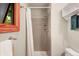 Simple bathroom with a tiled shower, white walls, neutral decor, and natural light from a nearby window at 1161 S Johnson Way, Lakewood, CO 80232