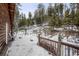 Log cabin back deck with wooden railings, partially covered in snow, offering a view of snowy woods at 721 Aspen Way, Evergreen, CO 80439