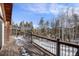 Wooden deck overlooking a snow covered landscape with pine trees at 721 Aspen Way, Evergreen, CO 80439