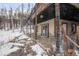 Exterior view of a log home with a lower level patio and fenced yard, partially covered in snow at 721 Aspen Way, Evergreen, CO 80439