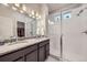 Bright bathroom featuring a double vanity, granite countertop, and glass-enclosed shower at 6153 N Ceylon St # 2-202, Denver, CO 80249