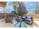 Outdoor patio area with stylish wicker furniture set against a backdrop of mature trees and a blue outbuilding at 330 W Fair Ave, Littleton, CO 80120