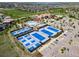 Wide aerial view of tennis and pickleball courts next to a clubhouse, pool, and golf course at 7720 S Queensburg Way, Aurora, CO 80016