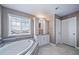 Well-lit bathroom featuring marble counters, custom vanity, soaking tub and white cabinetry at 7720 S Queensburg Way, Aurora, CO 80016