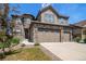 Attractive home showcasing stone accents, a well-manicured lawn, and an attached three car garage at 7720 S Queensburg Way, Aurora, CO 80016