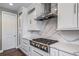 Close-up of stainless gas cooktop set in bright kitchen with white cabinetry and marble-style backsplash at 7720 S Queensburg Way, Aurora, CO 80016