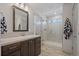 Bathroom with wood vanity, white countertop, large mirror, and walk-in shower at 1100 Blue Bell Rd, Berthoud, CO 80513