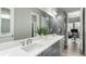 Stylish bathroom with dual sinks, sleek gray cabinets, quartz countertop, large mirrors, and modern lighting at 5839 Hay Market Trl, Parker, CO 80134
