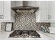 A detailed look at the kitchen stove with stylish backsplash and range hood at 5839 Hay Market Trl, Parker, CO 80134