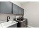 Well-equipped laundry room featuring sleek cabinets, sink, and modern washer and dryer for convenient chores at 5839 Hay Market Trl, Parker, CO 80134