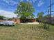 View of the backyard with a detached garage, partial car coverage, and a lush lawn with a shade tree at 7371 Granada Rd, Denver, CO 80221