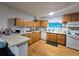 Traditional kitchen with wood cabinets, white appliances, and wood-look flooring at 7371 Granada Rd, Denver, CO 80221