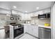 Updated kitchen featuring white cabinets, stainless steel appliances, modern lighting and a cozy fireplace at 2856 S Kenton Ct, Aurora, CO 80014