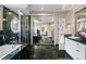 Elegant bathroom with marble walls, glass shower, soaking tub, and white vanity with counter space at 7645 Fox Creek Trl, Franktown, CO 80116