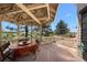 Covered outdoor deck with a dining table, string lights, and views of the surrounding greenery at 7645 Fox Creek Trl, Franktown, CO 80116