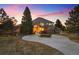 Stunning home exterior with circular driveway and lush landscaping at dusk at 7645 Fox Creek Trl, Franktown, CO 80116