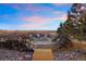 Outdoor firepit area with Adirondack chairs and a wooden boardwalk surrounded by wood piles and stone at 7645 Fox Creek Trl, Franktown, CO 80116