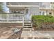 Exterior shot of front entrance features weathered stairs, gray siding, and lush green bushes at 180 S Nome St, Aurora, CO 80012