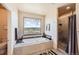Bright bathroom with a soaking tub with jets under a large window showcasing vast views at 8611 Coachlight Way, Littleton, CO 80125