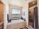 Bathroom featuring a soaking tub, a large window with views, and a separate shower at 8611 Coachlight Way, Littleton, CO 80125