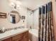 Bathroom with a vanity, round mirror, and a shower-tub combination with a decorative curtain at 8611 Coachlight Way, Littleton, CO 80125