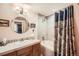 Well-lit bathroom with a shower-tub combo, elegant tiling, and round mirror at 8611 Coachlight Way, Littleton, CO 80125