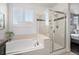 Bright bathroom with tub and shower, with tile surround, a window and stylish fixtures at 9080 Fig St, Arvada, CO 80005