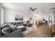 Open living room featuring a gray sectional sofa, hardwood floors, large windows and an open dining area at 9080 Fig St, Arvada, CO 80005