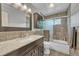 Bathroom featuring a vanity with stone countertops, dark cabinets, and tiled shower at 8032 Lee Ct, Arvada, CO 80005